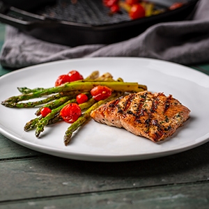grilled salmon with asparagus and red tomatoes on a plate