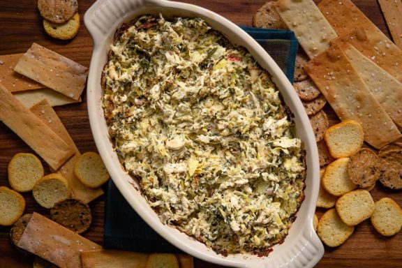 Bowl of tuscan chicken dip surrounded by crackers