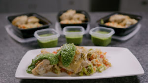 Lemon basil chicken thigh with quinoa and pesto plated as well in meal prep containers