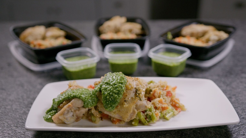 Lemon basil chicken thigh with quinoa and pesto plated as well in meal prep containers