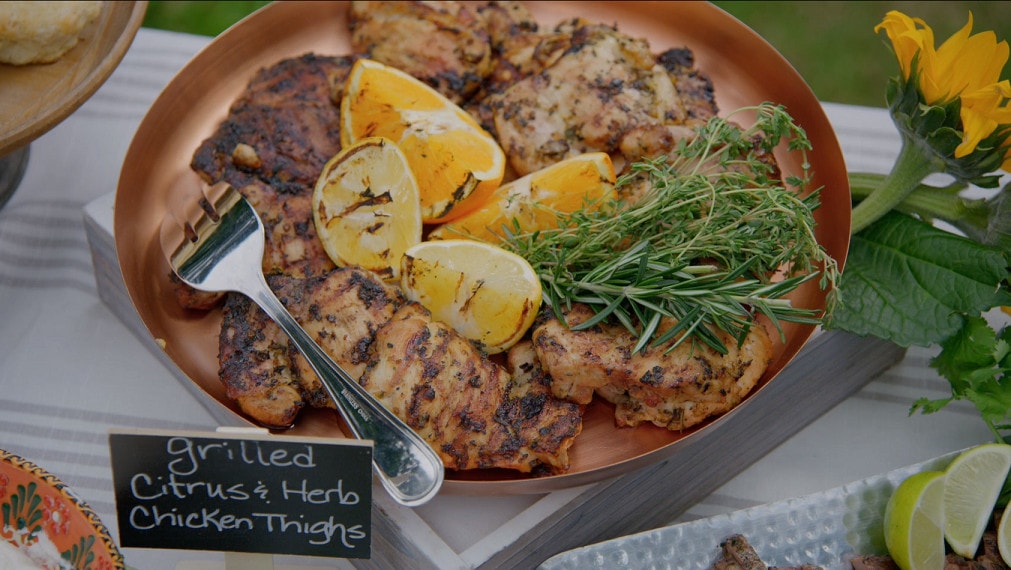 grilled chicken thighs on a plate with lemon and herb