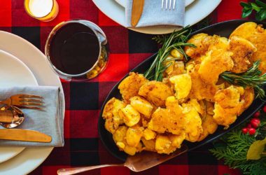 smashed potatoes in a dish surrounded by plates and silverware