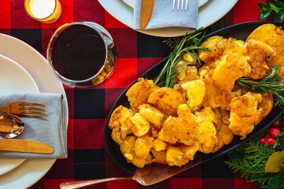smashed potatoes in a dish surrounded by plates and silverware