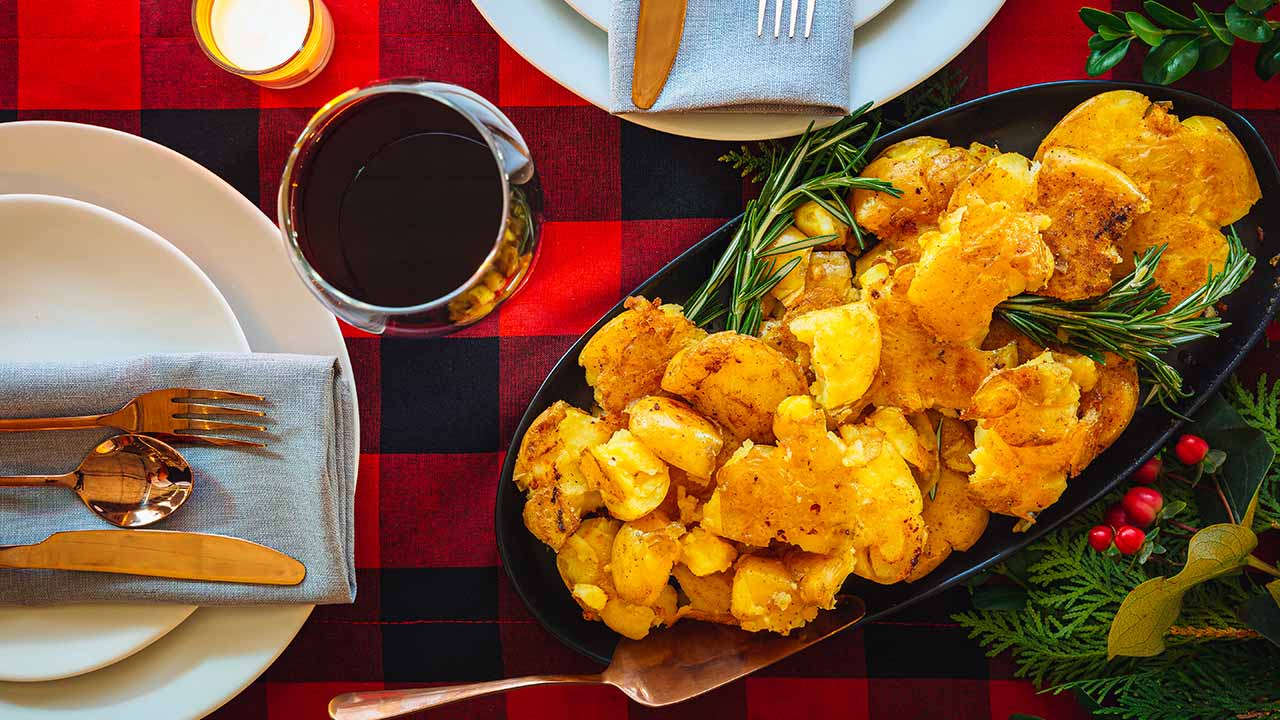 smashed potatoes in a dish surrounded by plates and silverware
