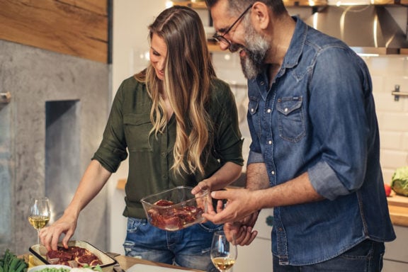 couple preparing steak dinner in kitchen on weeknight
