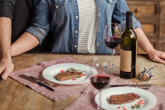 man and woman steak and wine romantic dinner