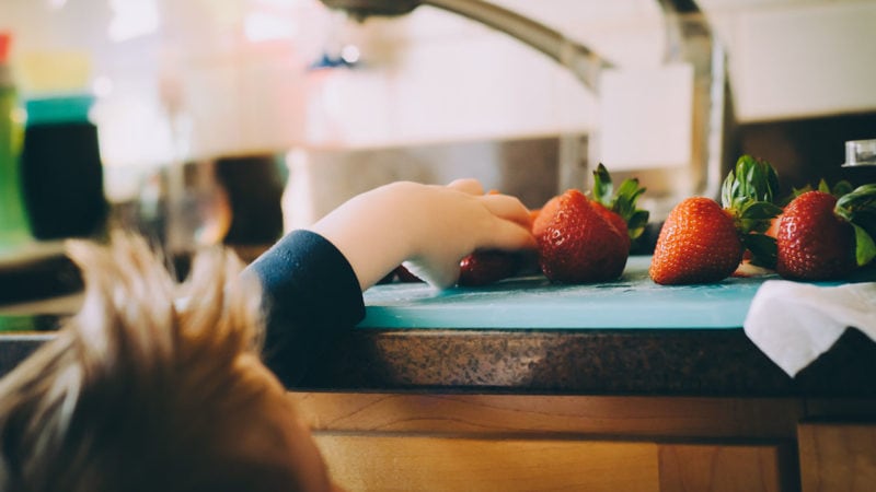 kids grabbing strawberries in kitchen