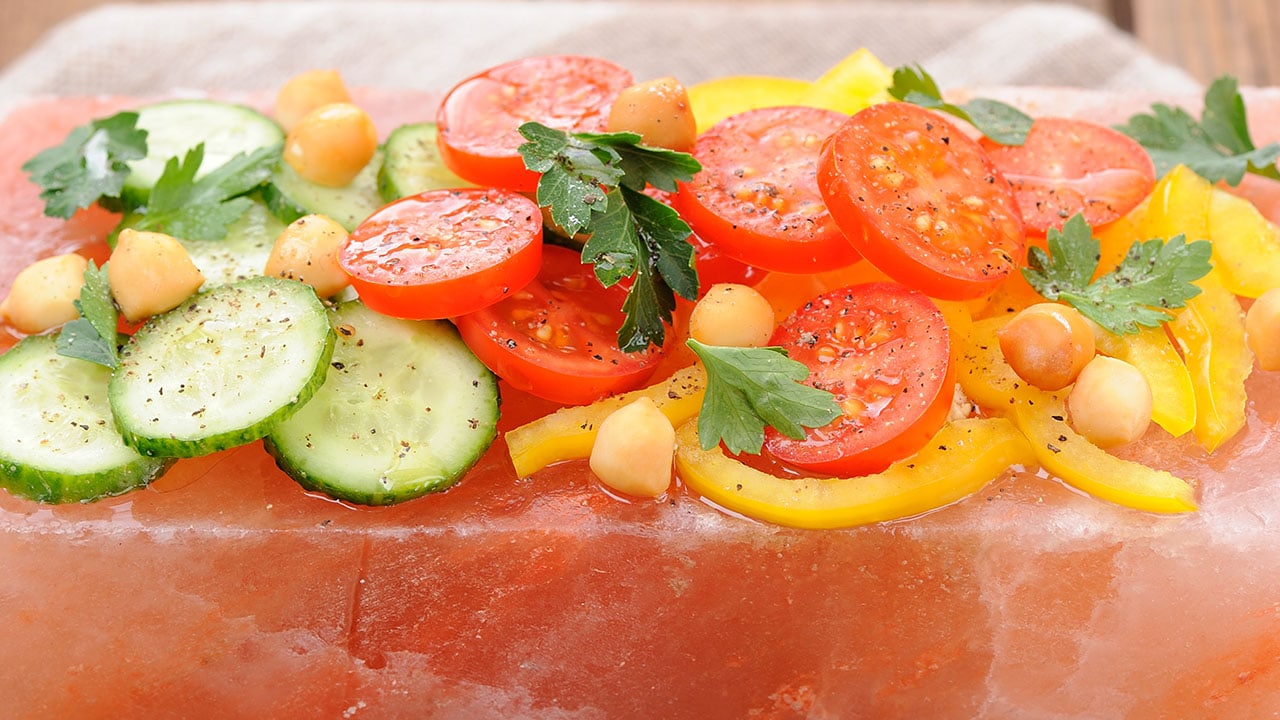 Vegetables on pink salt block on stripe napkin and wooden background