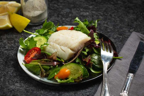baked cod filet on a bed of greens and vegetables