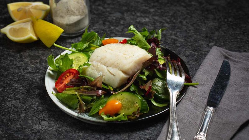 baked cod filet on a bed of greens and vegetables