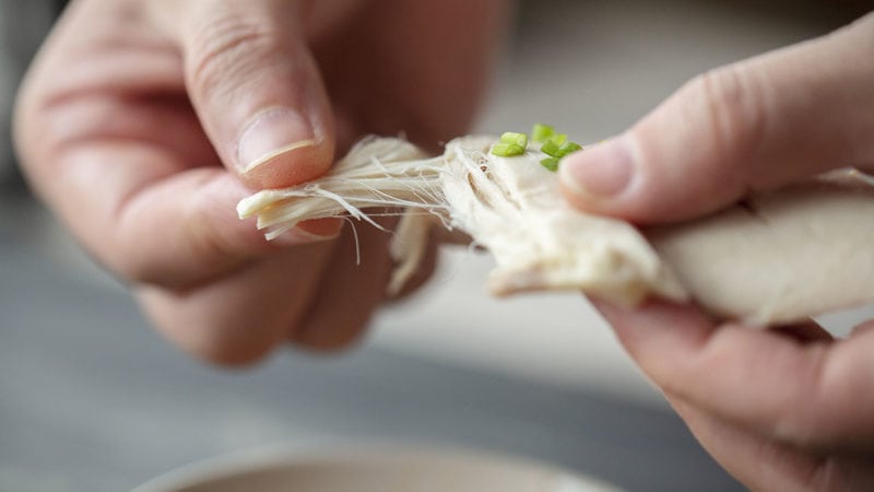 a person shredding chicken