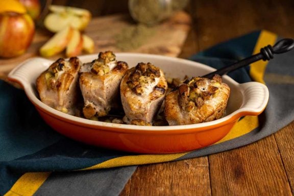 baked stuff pork chops in a dish next to apples