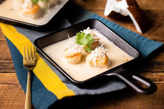seared scallops in coconut cream sauce in a skillet