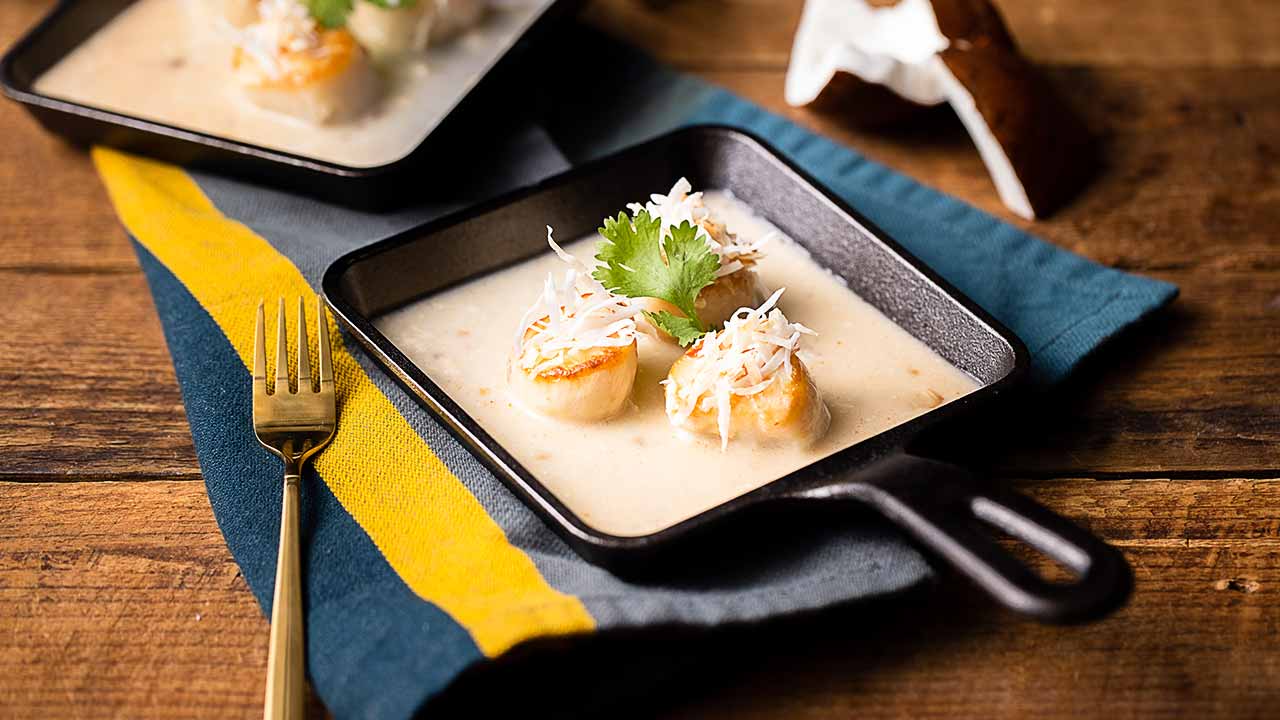 seared scallops in coconut cream sauce in a skillet