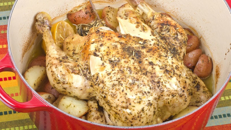 baked chicken in red dutch oven with potatoes