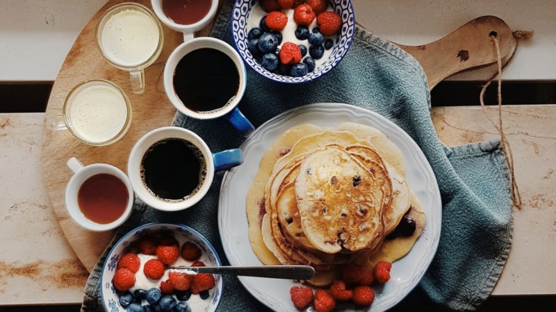 pancake breakfast board with yogurt, berries, and coffee