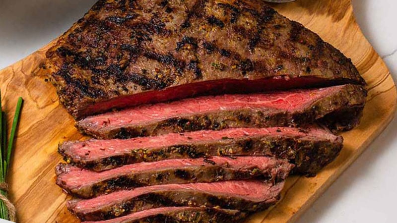 Sliced flank on a cutting board with chives