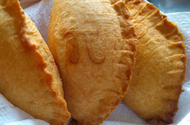 Three meat hand pies on a paper towel with a pi symbol on one of them