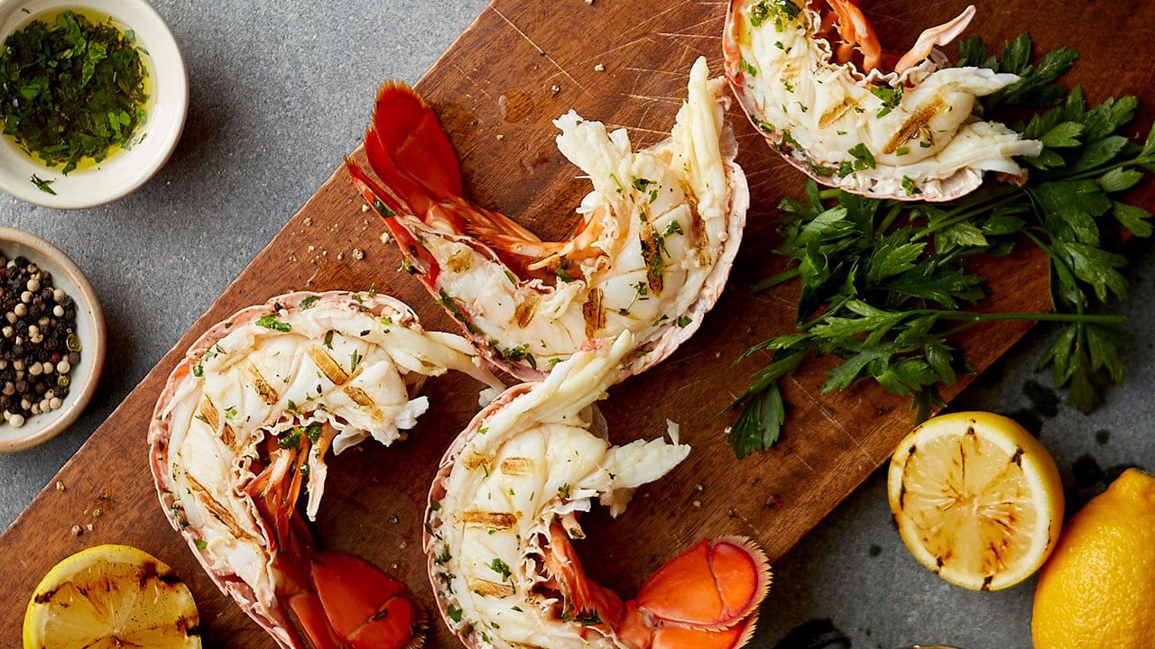 obster tails surrounded by various ingredients on on a cutting board