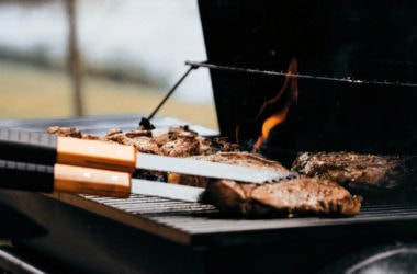 flipping steaks on a grill with tongs