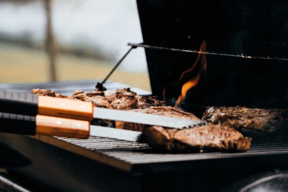 flipping steaks on a grill with tongs