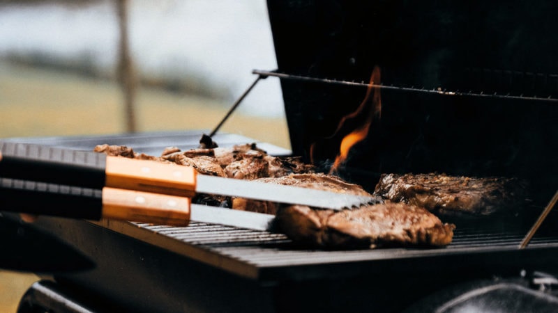 flipping steaks on a grill with tongs
