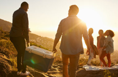 A group of people carrying a cooler with the sun shining