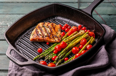 Sockeye salmon filet, tomatoes, and asparagus in a grill pan