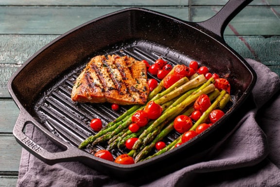 Sockeye salmon filet, tomatoes, and asparagus in a grill pan