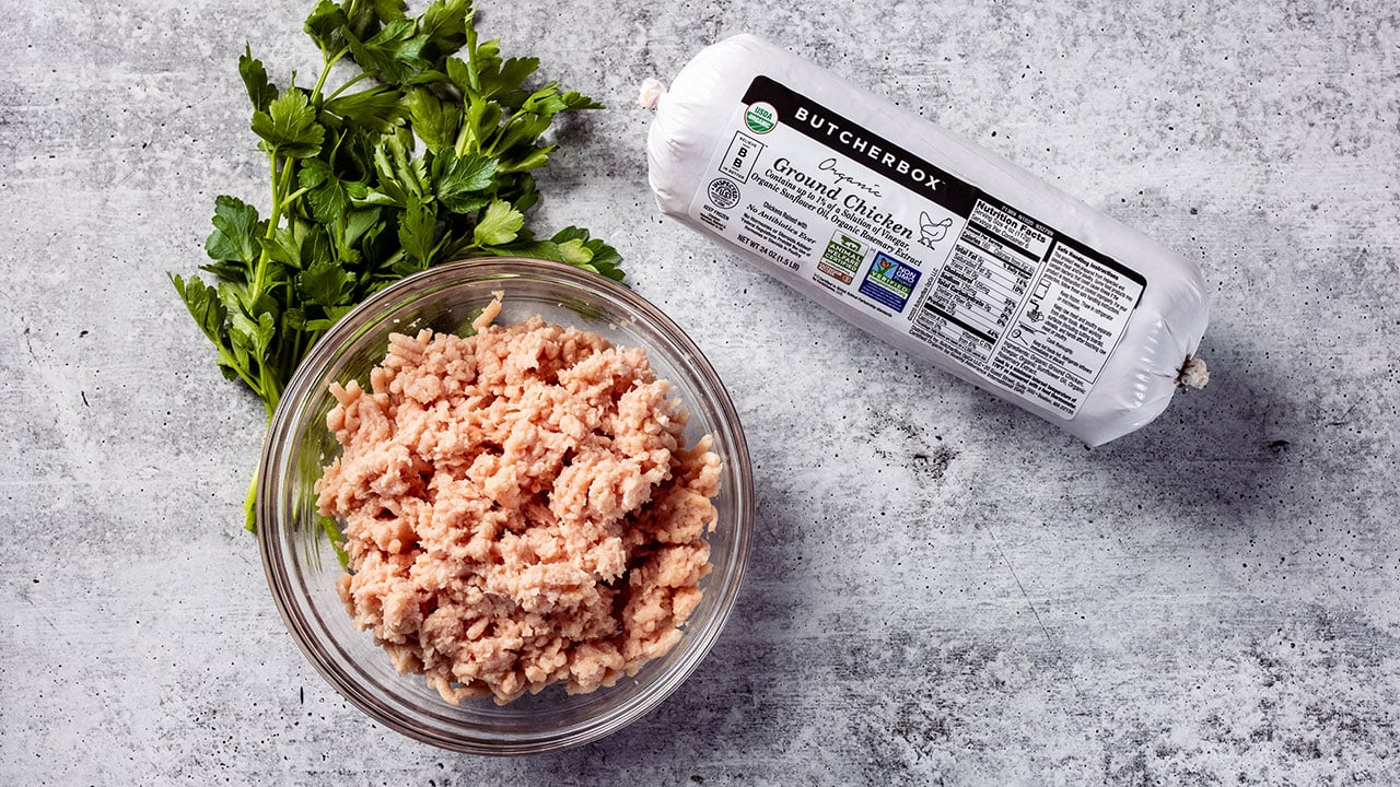 raw ground chicken in a bowl next to package of ButcherBox ground chicken