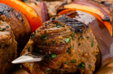 close up of steak tips and vegetables on a metal skewer