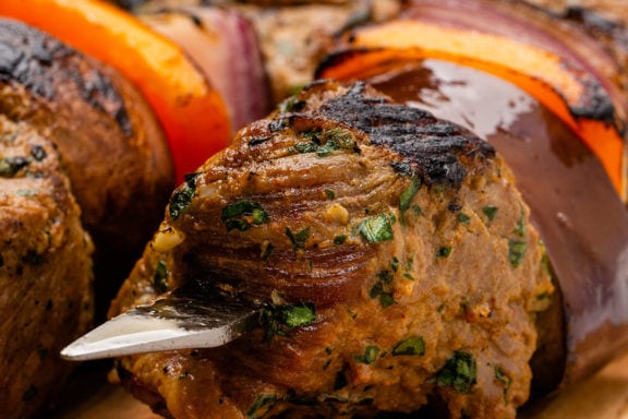 close up of steak tips and vegetables on a metal skewer