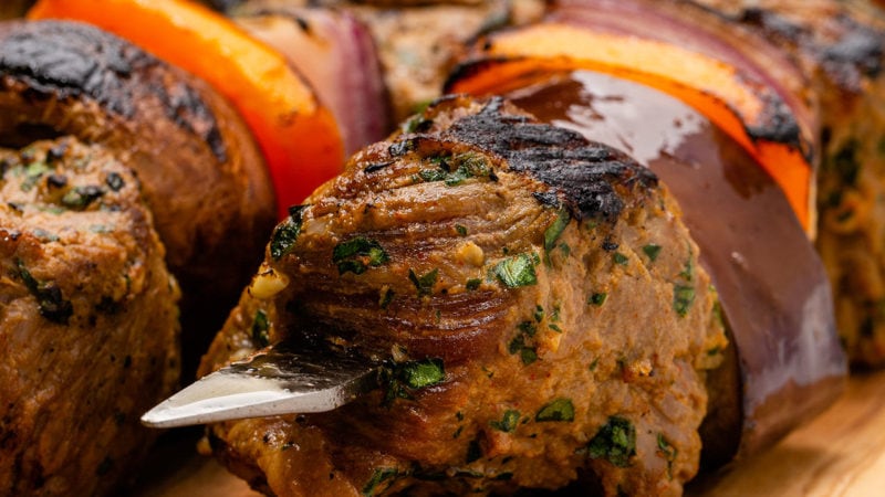 close up of steak tips and vegetables on a metal skewer