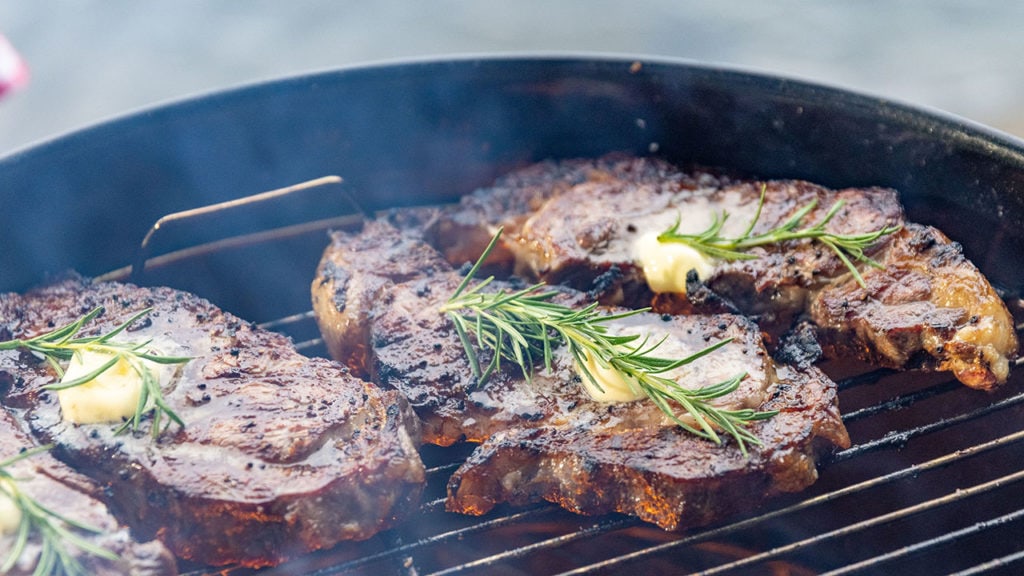 steaks marinating in butter on the grill