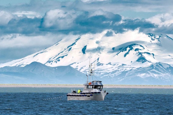 fishing boat out on the water with a snow-covered mountain in the background