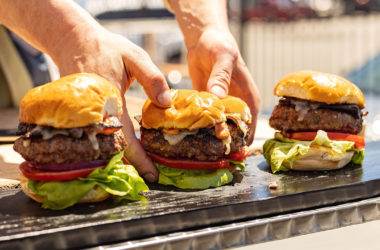 hands grabbing three bacon cheeseburgers
