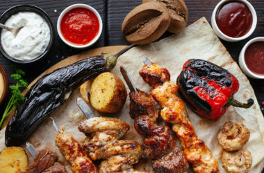 Skewered meat on a table with different hot sauces and dips in ramekins