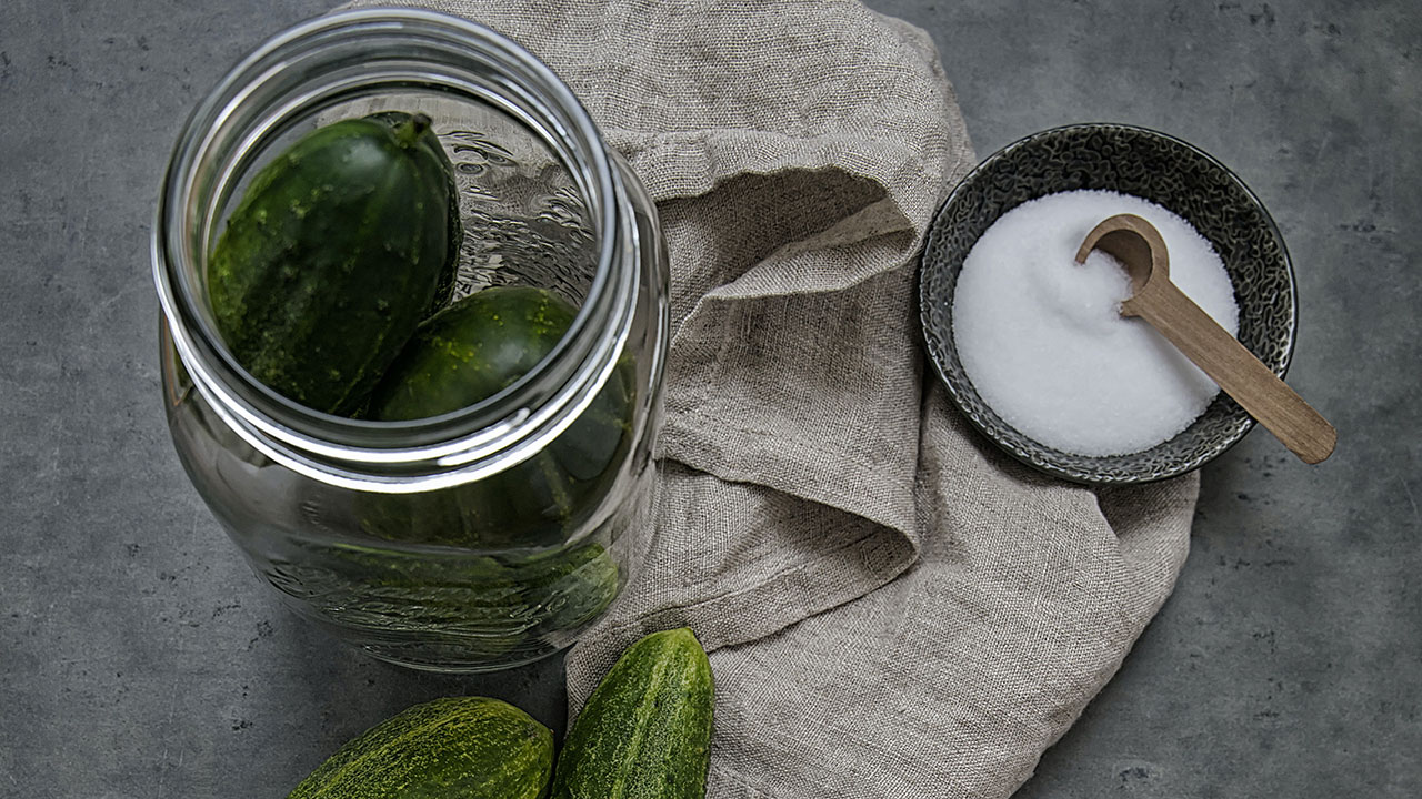 jar of pickles and a bowl of salt on top of a cloth