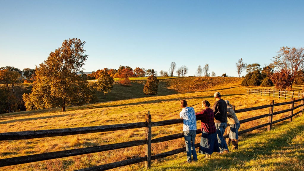 a farm family standing by a fence