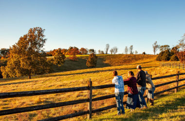 a farm family standing by a fence