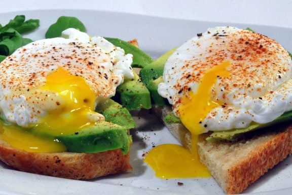 two slices of toast topped with avocado and poached eggs