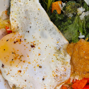 roasted kale, carrots, chili mayo, and fried egg over crispy rice in a bowl