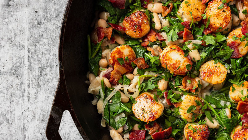 scallops spinach beans and bacon in a skillet