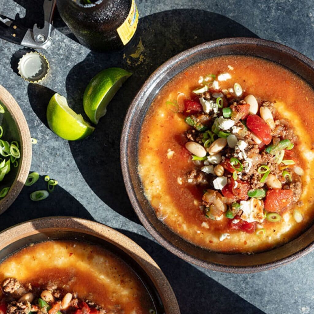 A bowl of ButcherBox's hearty bison and bean chili topped with cheese and garnished with green onions.
