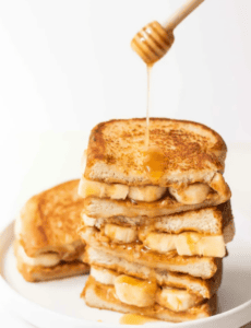 honey being drizzled over a stack of pb&honey sandwiches